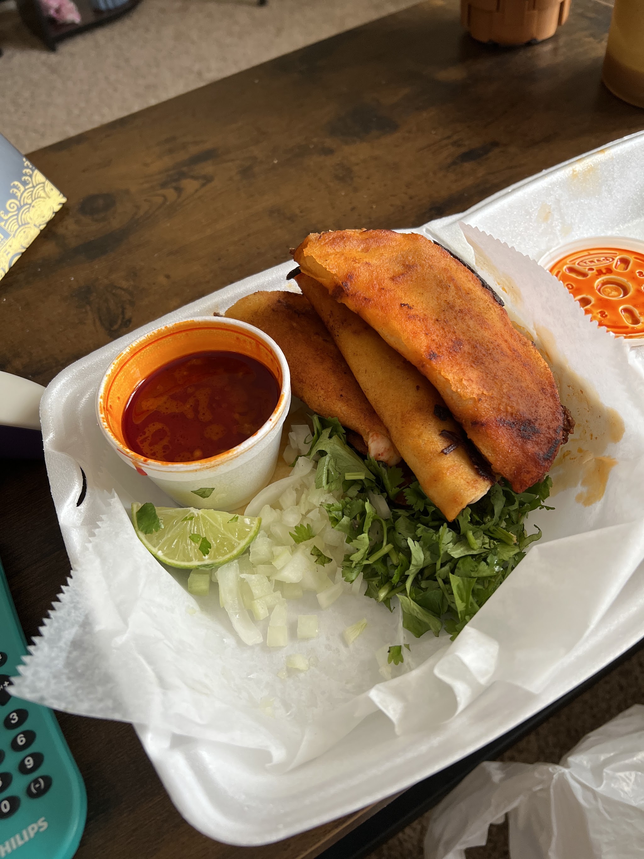 Crispy quesabirria tacos with a cup of red consomé, lime, onion and cilantro