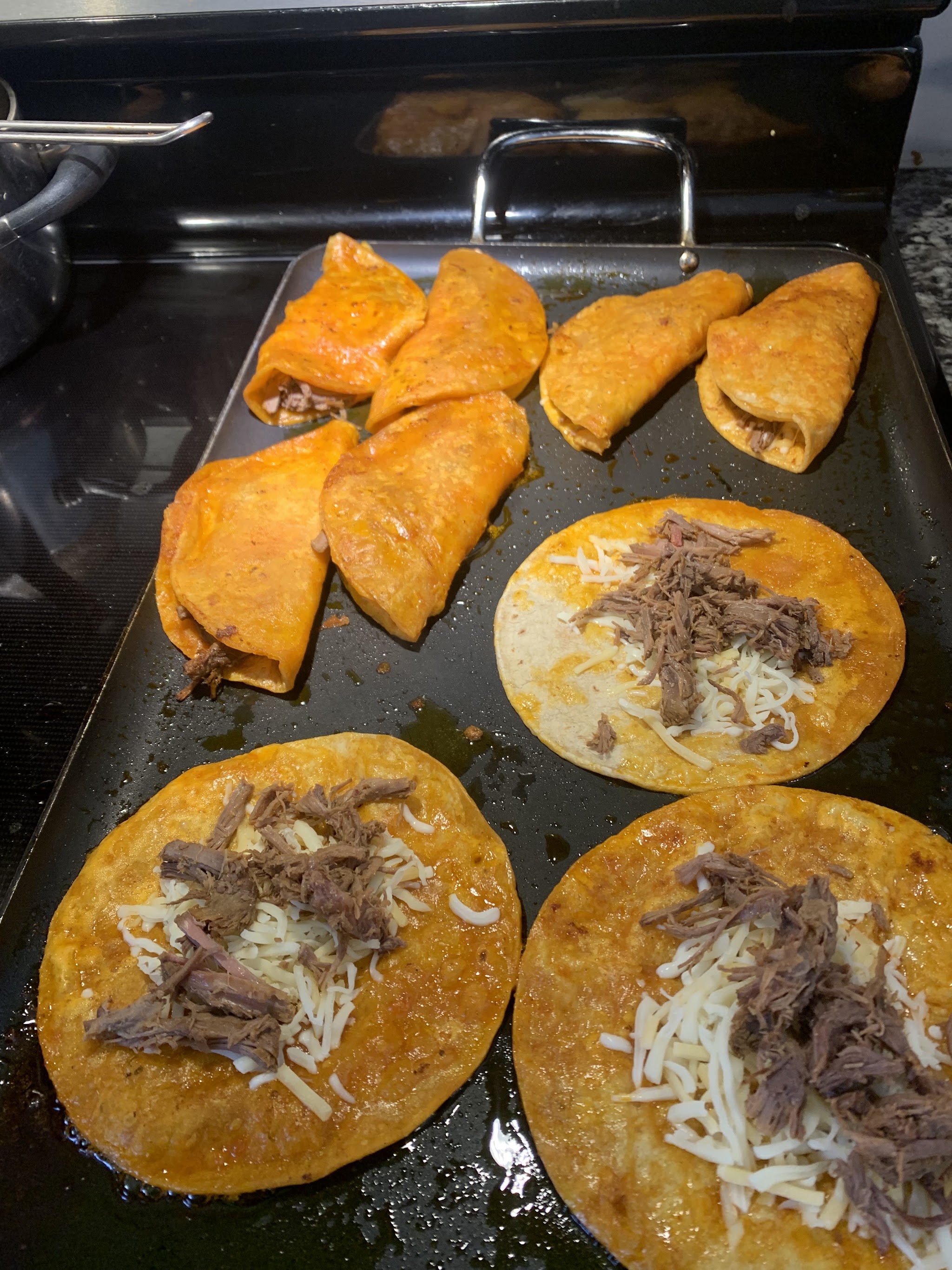 Quesabirria tortillas with beef and cheese on the griddle