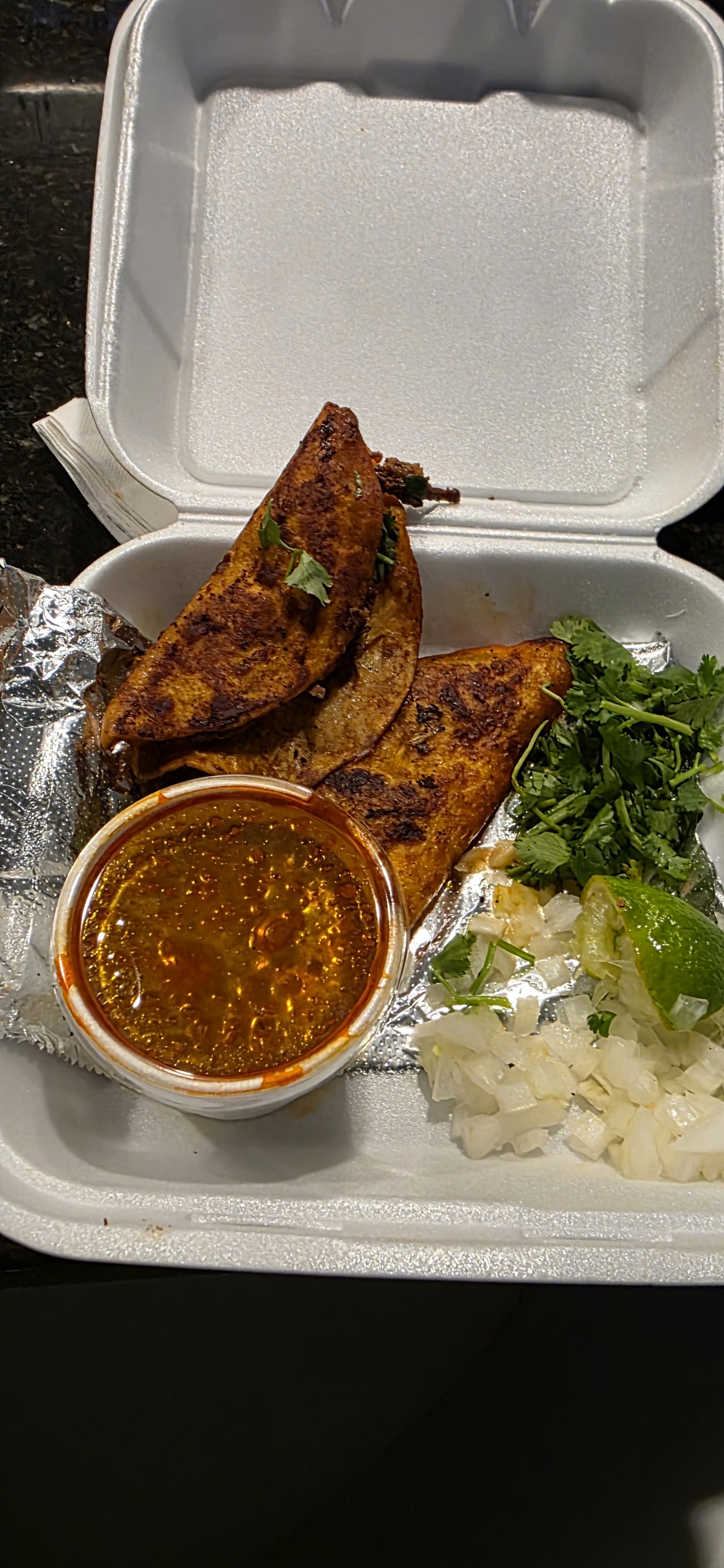 Quesabirria tacos with a cup of consomé, onion and cilantro