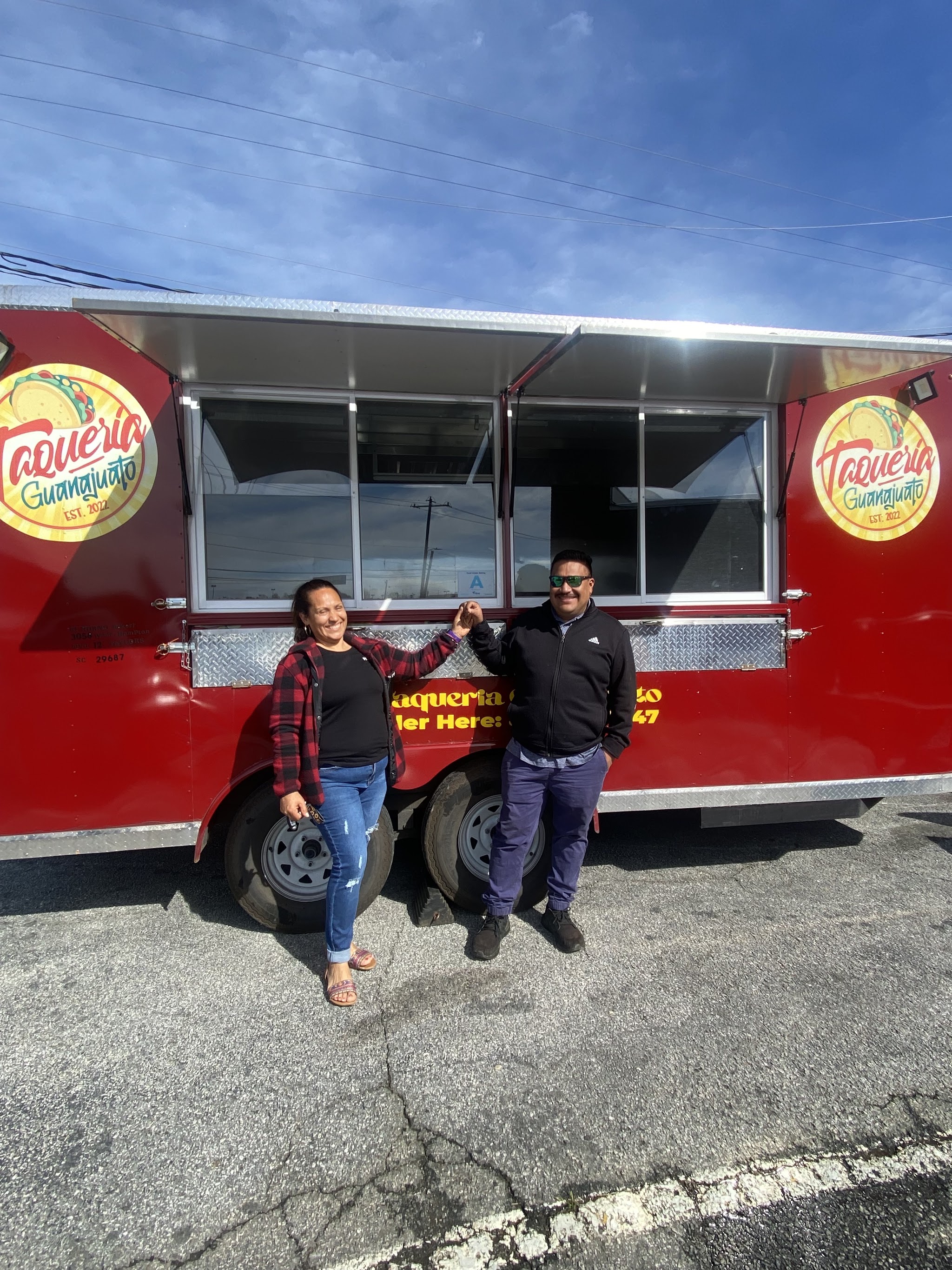 Two people standing in front of the red Taqueria Guanajuato truck